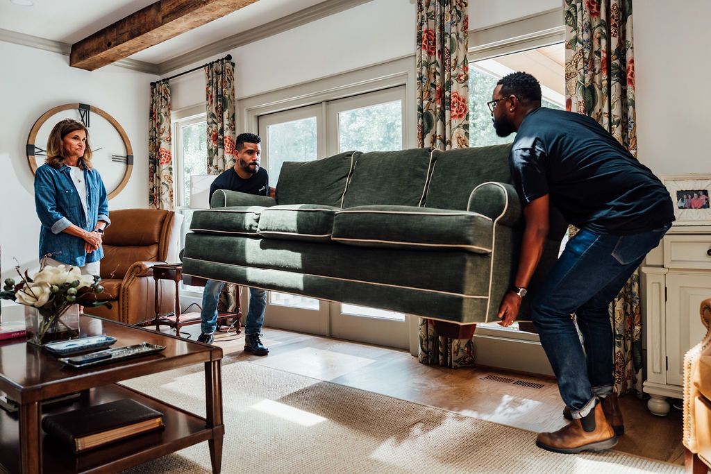Two LoadUp Loaders lifting a green sofa in a Montclair living room while the customer watches