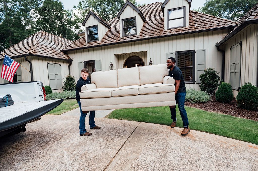 Two LoadUp Loaders carrying a three-seat sofa down a driveway to the pickup truck