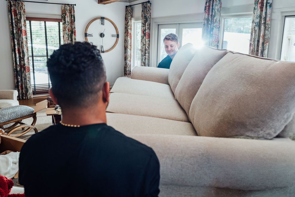 A LoadUp Loader guiding a cream sofa through a Montclair living room toward the patio doors