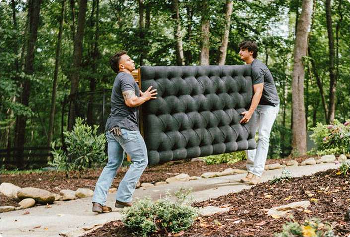 Two men carrying a large piece of living room furniture